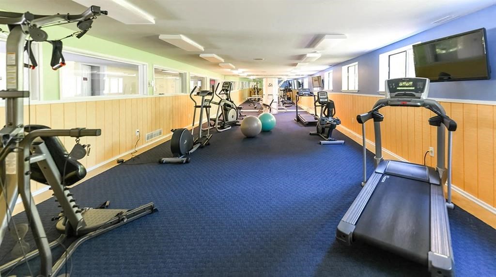 a gym with exercise equipment on the floor and a tv