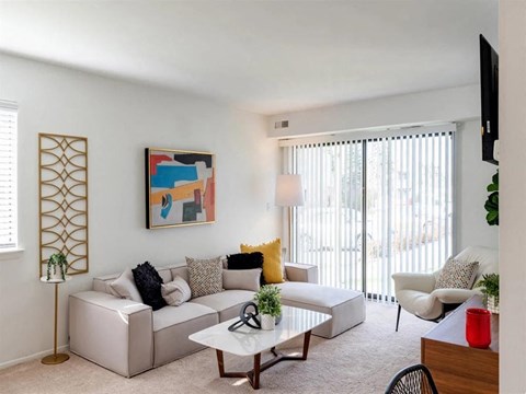 A living room with a white couch, a coffee table, and a painting on the wall.