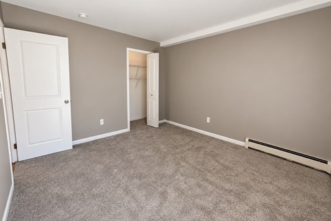 A room with a carpeted floor and two doors, one of which is open.