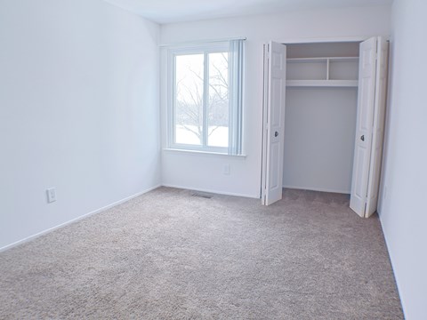 A room with a carpeted floor and a window.