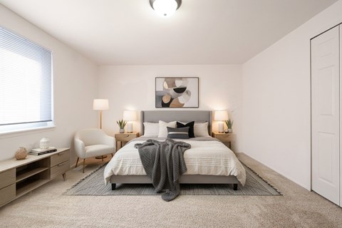 A bedroom with a bed, chair, and nightstands.