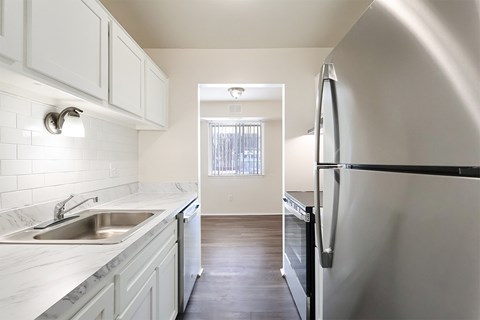 A kitchen with white cabinets and a black fridge.