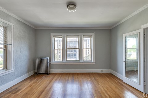 an empty living room with wood floors and a window