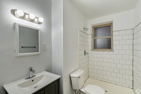 A white bathroom with a sink, toilet, and mirror.