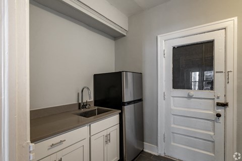 A small kitchen with a black fridge and white cabinets.