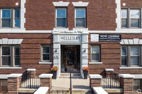 The front of a brick building with a sign that says "Wellesley" and "Now Leasing".