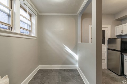 A kitchen with a refrigerator, trash can, and a window.