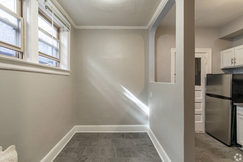 A kitchen with a stainless steel refrigerator and a window with blinds.
