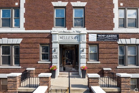 The front of a brick building with a sign that says "Wellesley" and "Now Leasing".