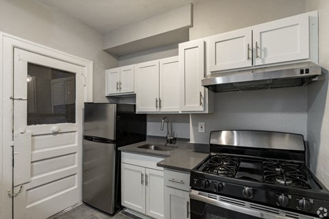 A kitchen with white cabinets and a black stove top oven.