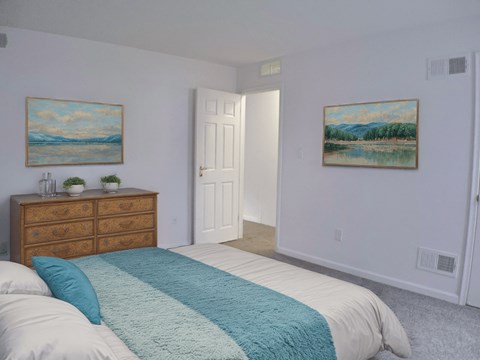 A bedroom with a bed, dresser, and two paintings on the wall.