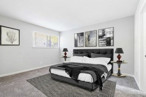 A bedroom with a large bed and two lamps.