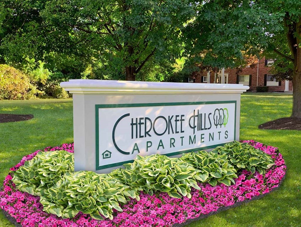 A sign for Cherokee Hills Apartments is surrounded by flowers.
