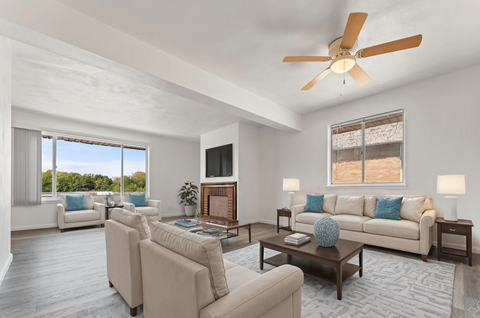 A living room with a white ceiling fan and a large window.
