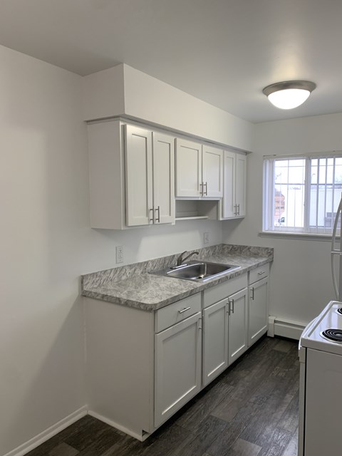A kitchen with white cabinets and a marble countertop.