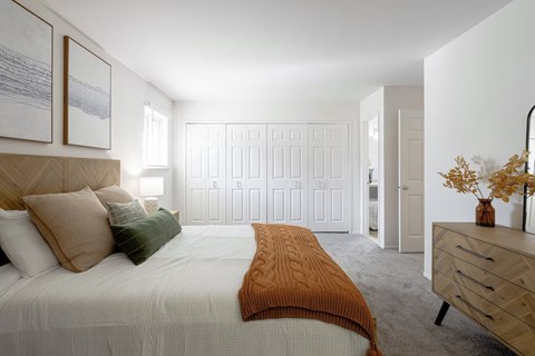A bedroom with a bed, dresser, and two framed pictures on the wall.