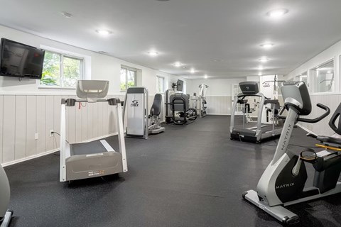 A gym with a variety of exercise equipment including treadmills, stationary bikes, and weight machines.