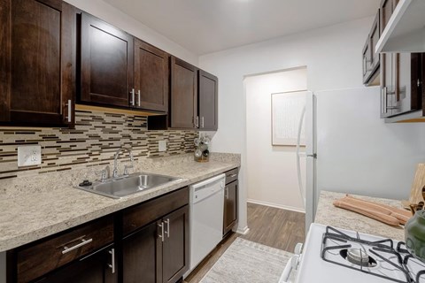 A kitchen with a white stove top oven and a white dishwasher.