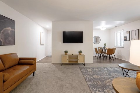 A living room with a brown couch and a flat screen TV mounted on the wall.