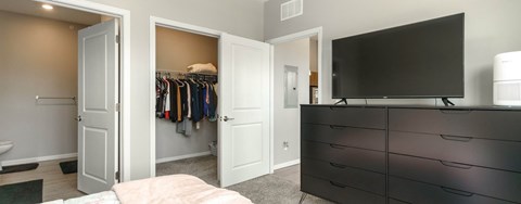 A black TV is on top of a black dresser in a bedroom.