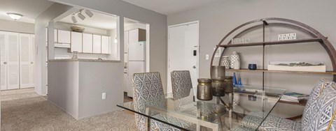 A glass table with chairs and a bar area in a room.