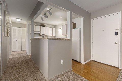 A kitchen area with a refrigerator, cabinets, and a countertop.
