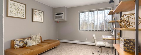 A living room with a couch, a chair, and a window with blinds.