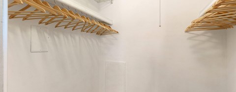 A white closet with wooden hangers.