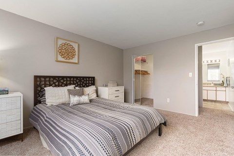 A bedroom with a large bed and a carpeted floor.