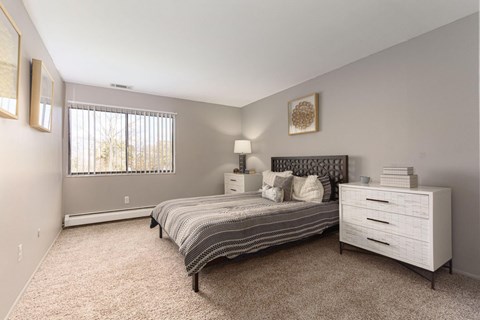 A bedroom with a bed, nightstand, and window.