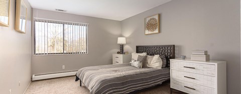 A bedroom with a bed, nightstand, and window.