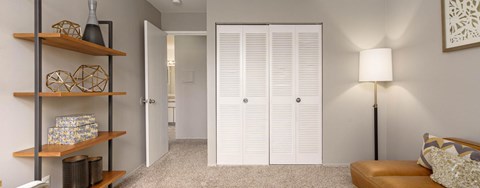 A living room with a couch, a lamp, and a shelf with decorative items.