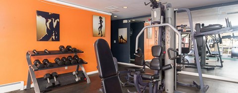 A gym with orange walls and a variety of exercise equipment.
