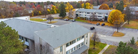 A parking lot is in front of a building with a grey roof.