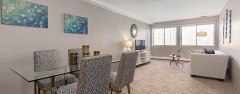 A living room with a glass dining table and chairs.