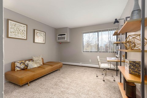 A living room with a brown couch and two pictures on the wall.