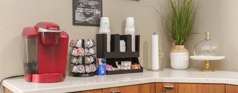 A red coffee maker sits on a counter with a variety of coffee-making supplies.