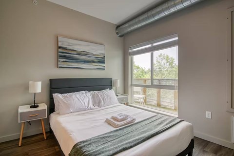 A bedroom with a large bed and a painting on the wall.