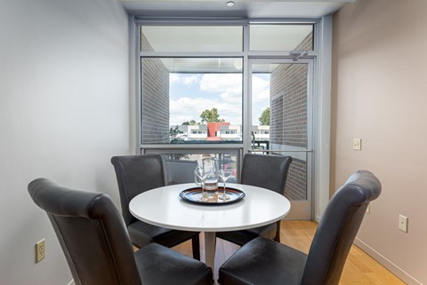 A dining room with a table and chairs and a view of the outside.