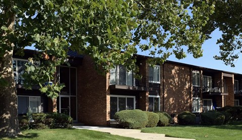 A building with a brick facade and a green lawn in front.
