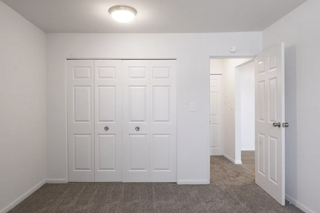 A room with white doors and carpeted floor.