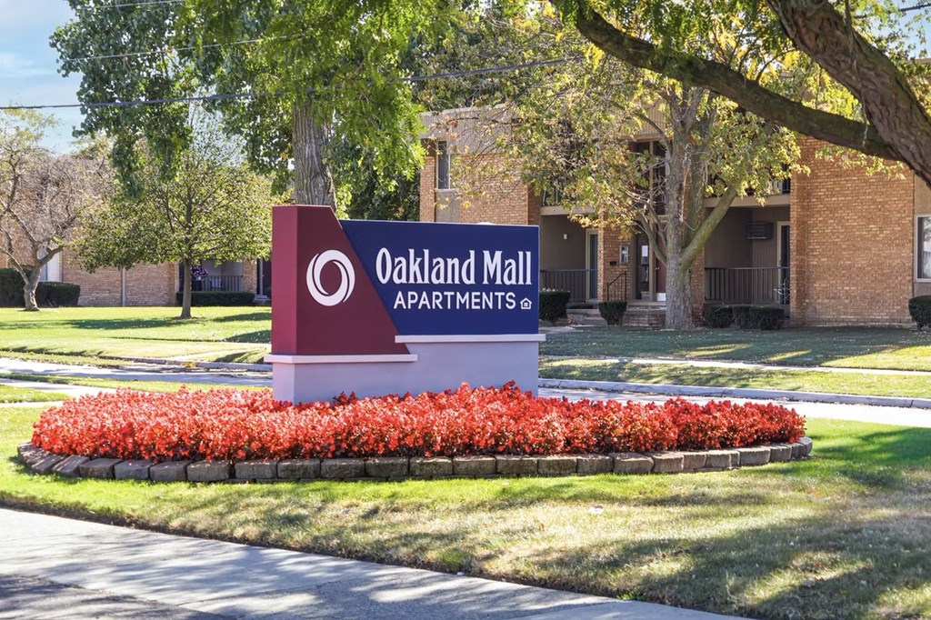 A sign for Oakland Mall Apartments is in front of a building.