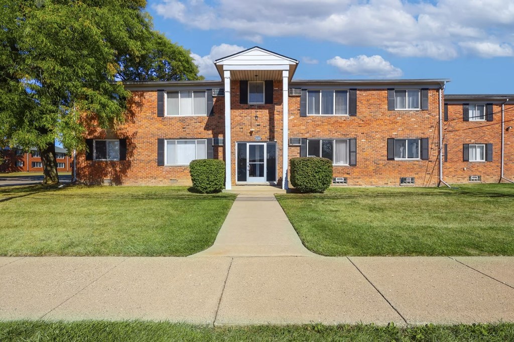 A brick building with a white entrance and a tree in front.