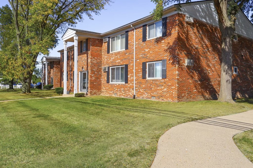 A red brick building with a white trim and a green lawn in front.