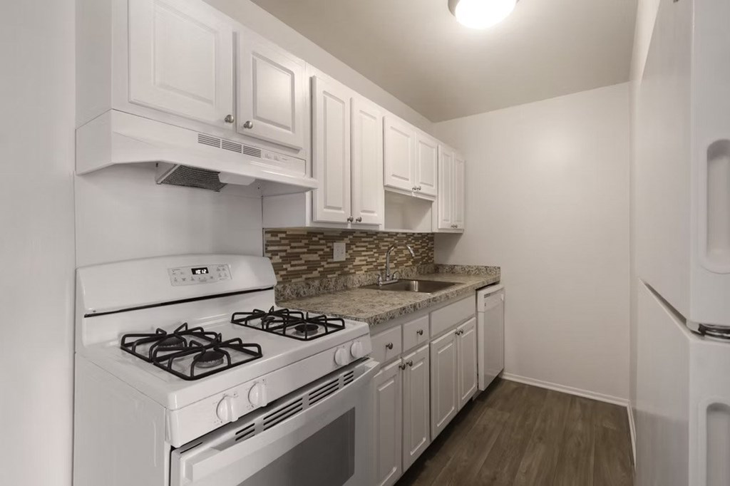 A kitchen with white cabinets and a white stove top oven.