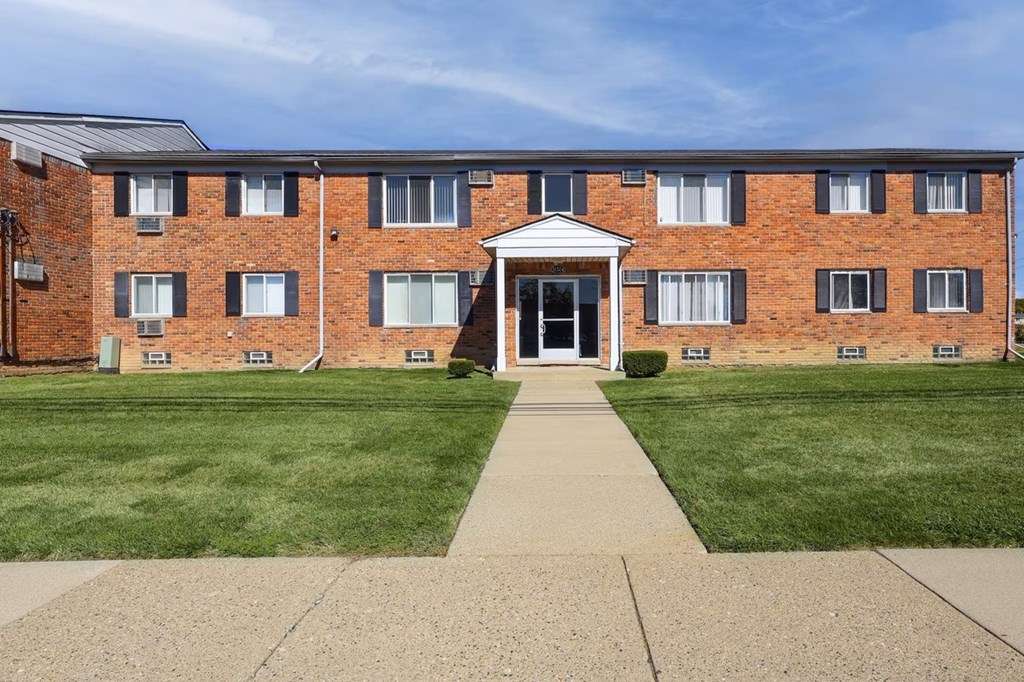 A brick building with a white entrance and a walkway leading to it.