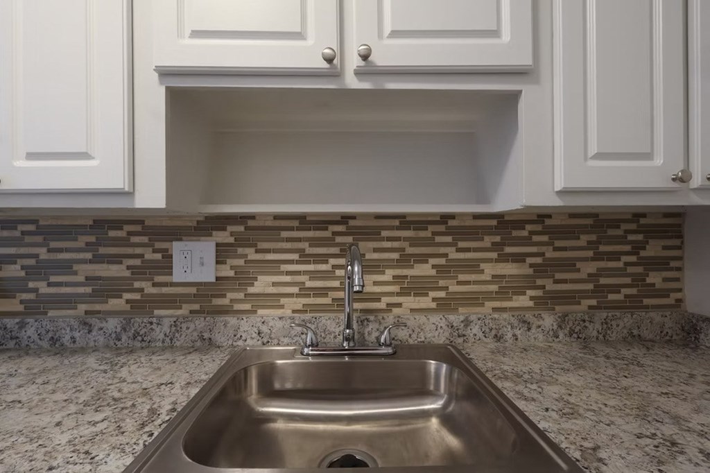A kitchen with a sink and a backsplash.