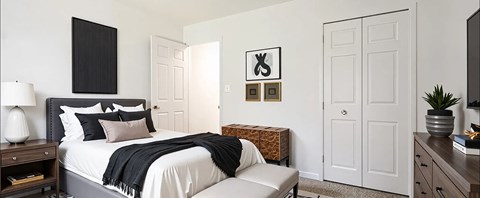 A bedroom with a large bed and a bench.