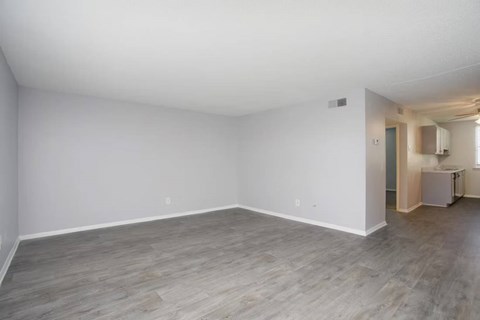A large empty room with wooden flooring and white walls.