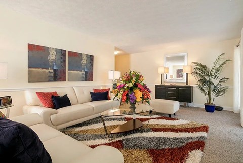 A living room with a white couch, a coffee table, and a large painting on the wall.